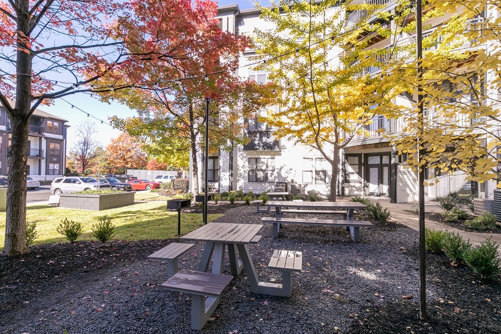 a park with benches and trees in front of a building