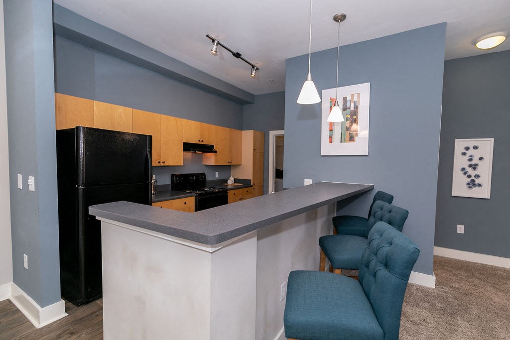 a kitchen with a bar and a black refrigerator
