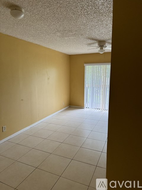 A room with a ceiling fan and a window with blinds.