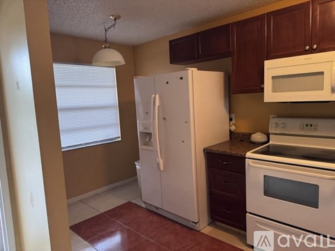 A kitchen with brown cabinets and white appliances.