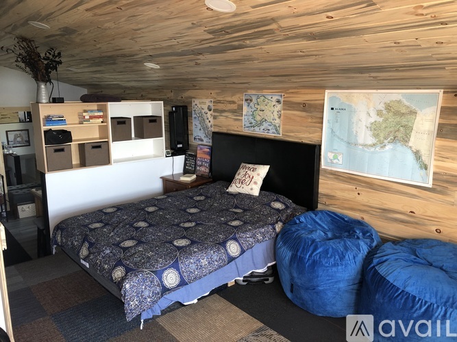 A bedroom with a bed, bean bag chairs, and a map on the wall.
