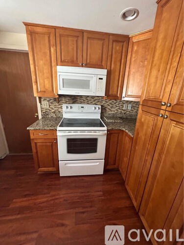 A kitchen with wooden cabinets and a white stove top oven.