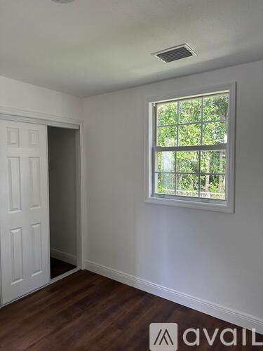 A hallway with wooden floors and a wooden door with a glass panel.