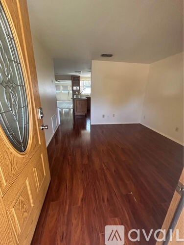 A hallway with wooden floors and a wooden door with a glass panel.