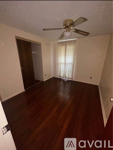 A room with a ceiling fan and wooden flooring.