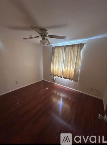 A room with a ceiling fan and a window with curtains.