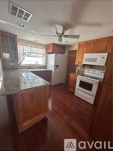 A kitchen with wooden cabinets and a granite countertop.