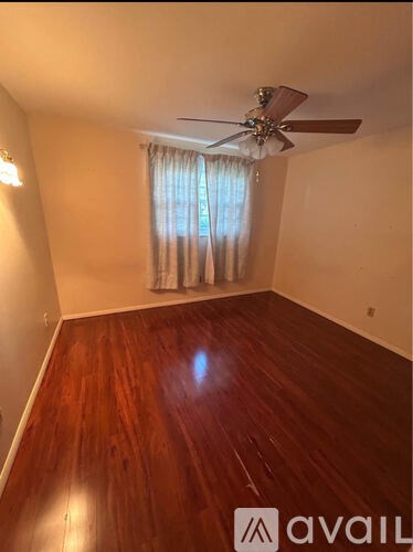 A room with wooden flooring and a ceiling fan.