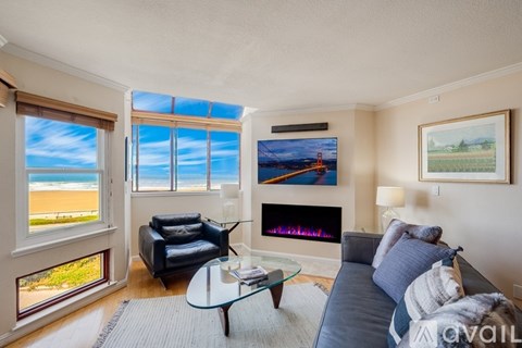 A living room with a couch, a fireplace, and a painting of a beach scene on the wall.