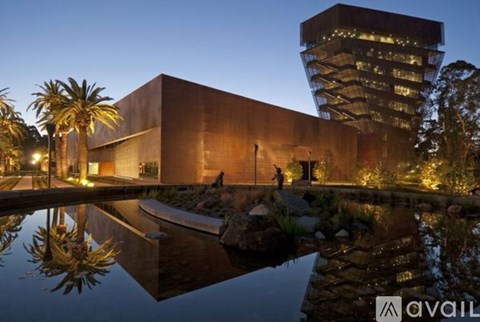 A modern building with a tall tower and a reflective pool in front.