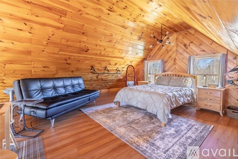 A cozy bedroom with a black leather sofa and a large bed with a wooden headboard.