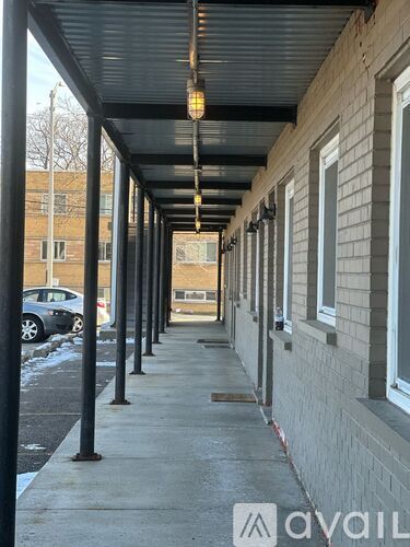 A long covered walkway with a metal roof and pillars on the side of a building.