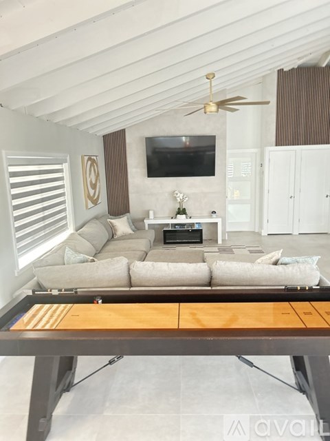 A modern living room with a large couch and a flat screen TV mounted on the wall.