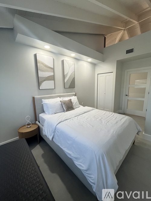 A bedroom with a large bed and two pictures on the wall.