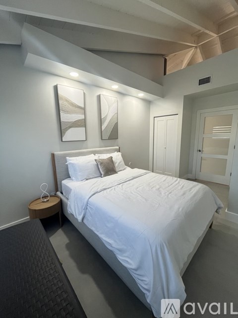 A bedroom with a large bed and two pictures on the wall.