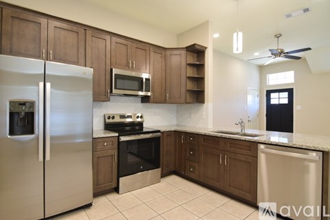 A kitchen with a refrigerator, oven, microwave, and sink.