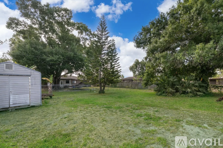 A backyard with a shed, trees, and a fence.
