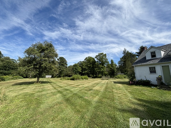 A large grassy field with a house and trees in the background.