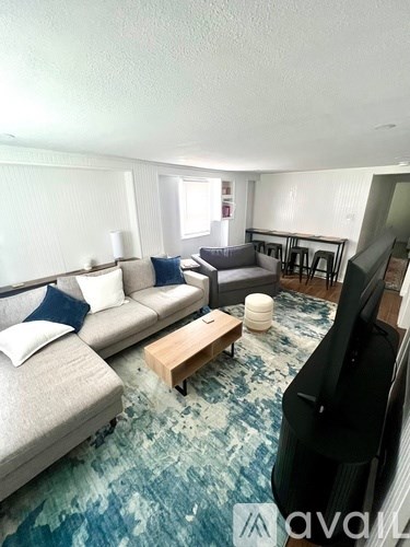 A living room with a grey couch, a wooden coffee table, and a television.