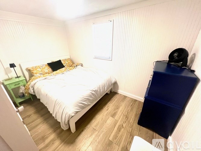 A bedroom with a white bed and a blue chair.