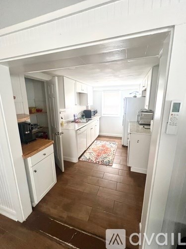 A kitchen with white appliances and brown flooring.