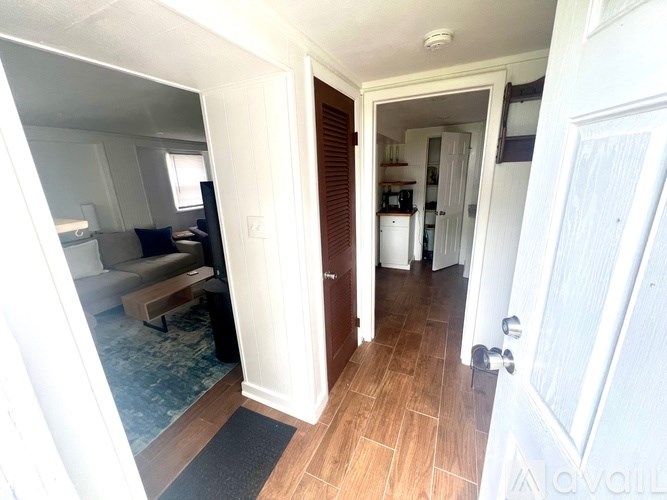 A hallway with a door on the right and a glass table with a couch in the background.