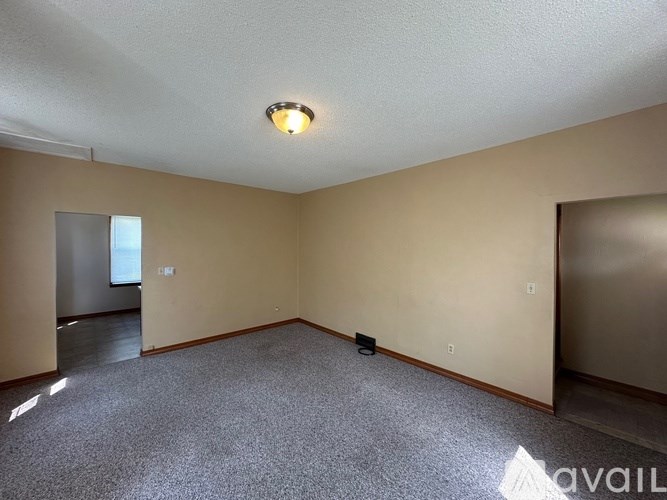 A spacious room with a carpeted floor and a ceiling light.