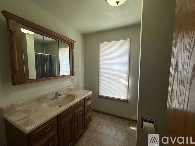 A bathroom with a sink, mirror, and a window with blinds.