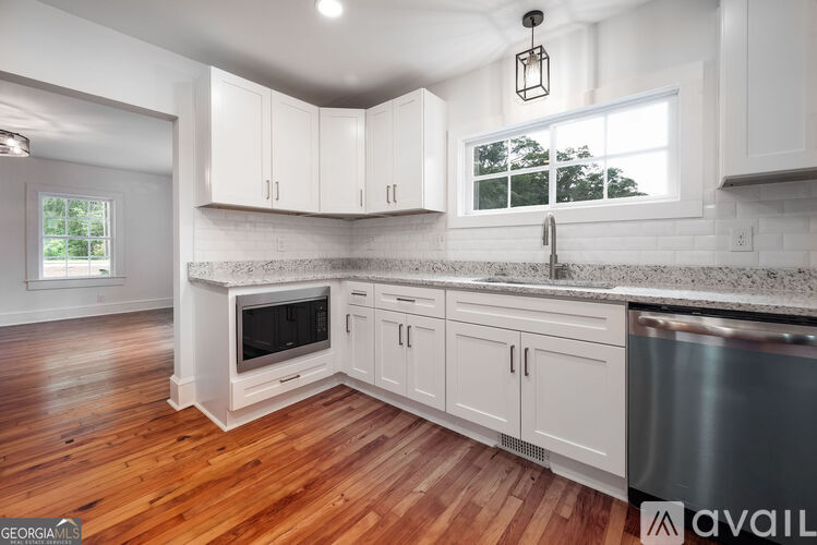 A kitchen with white cabinets and a wooden floor.