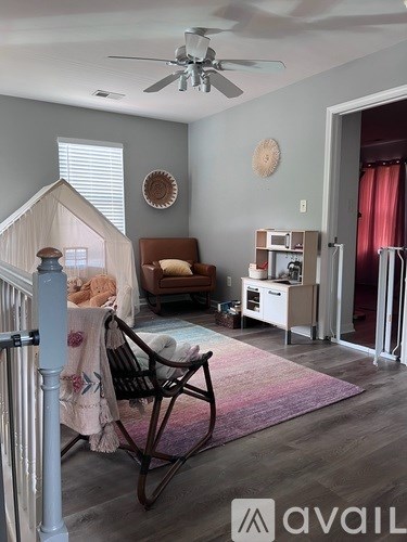 A living room with a rocking chair and a small house-like structure in the corner.