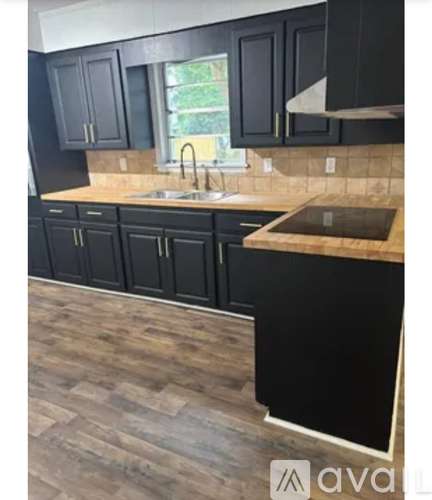 A kitchen with black cabinets and a wooden floor.