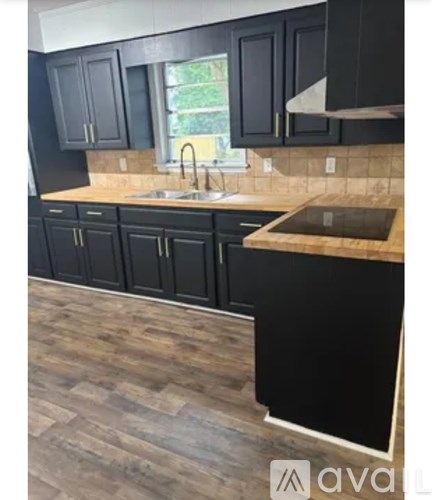 A kitchen with black cabinets and a wooden floor.