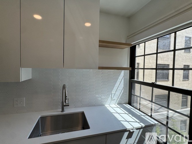 A modern kitchen with a stainless steel sink and white cabinets.
