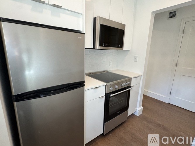 A kitchen with a stainless steel refrigerator, microwave, and oven.