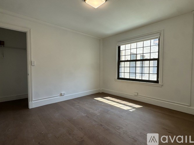 A room with a window and wooden flooring.