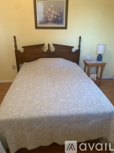 A bed with a white comforter and a wooden headboard.