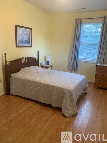 A bedroom with a bed, nightstand, and window.