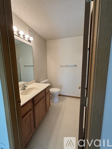 A bathroom with a toilet, sink, mirror and lights.