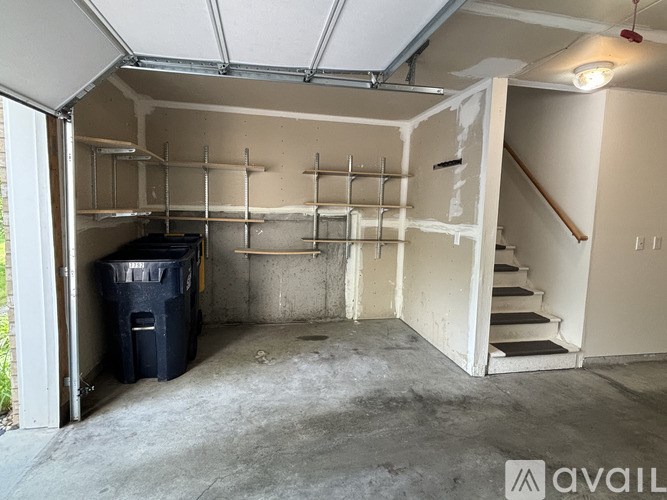 A room with a staircase and a trash bin.