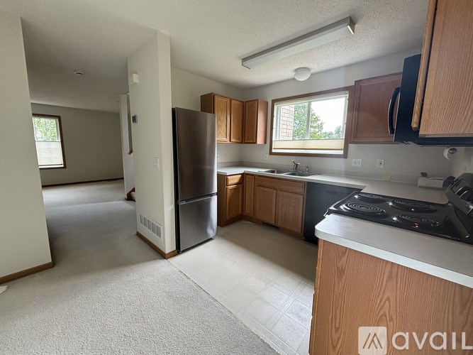 A kitchen with a refrigerator, sink, and cabinets.