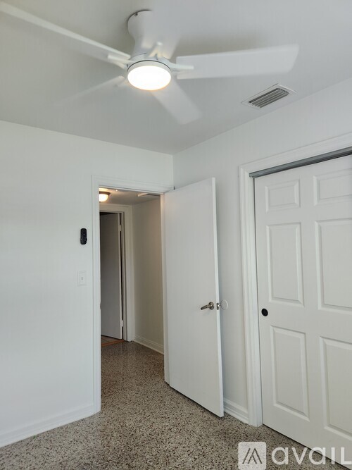 A white room with a ceiling fan and a door.