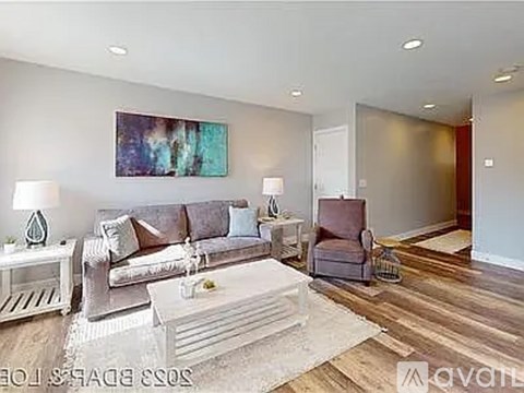 A living room with a grey couch, a white coffee table, and a painting on the wall.