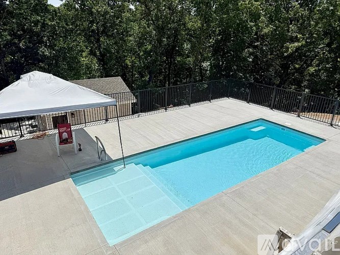A swimming pool surrounded by a fence and trees.