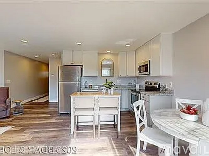 A kitchen with white cabinets and a dining table set for two.