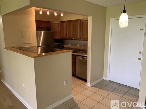 A kitchen with a stainless steel refrigerator and wooden cabinets.
