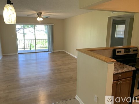 A living room with a kitchen area in the back.