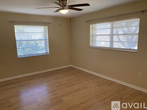A room with a ceiling fan and two windows.