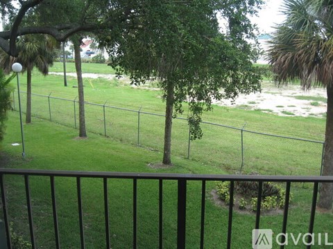 A balcony view of a green lawn and trees.