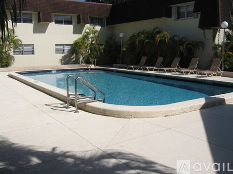 A pool with a metal ladder and chairs around it.