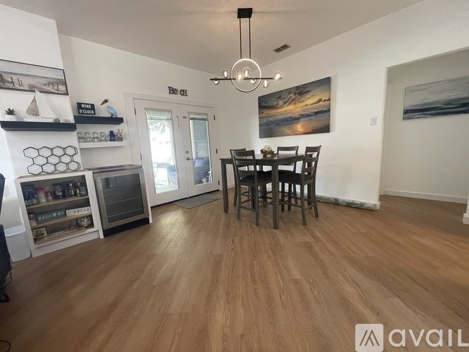 A living room with a wooden floor and a dining table with chairs.